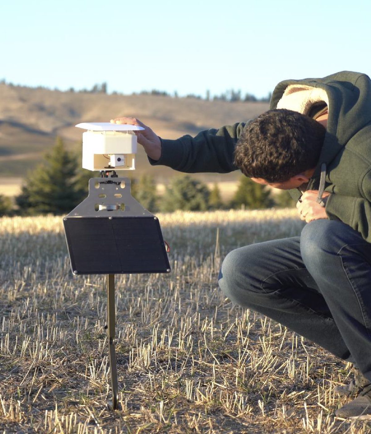 A team member installing a FarmGazer unit in a harvested field