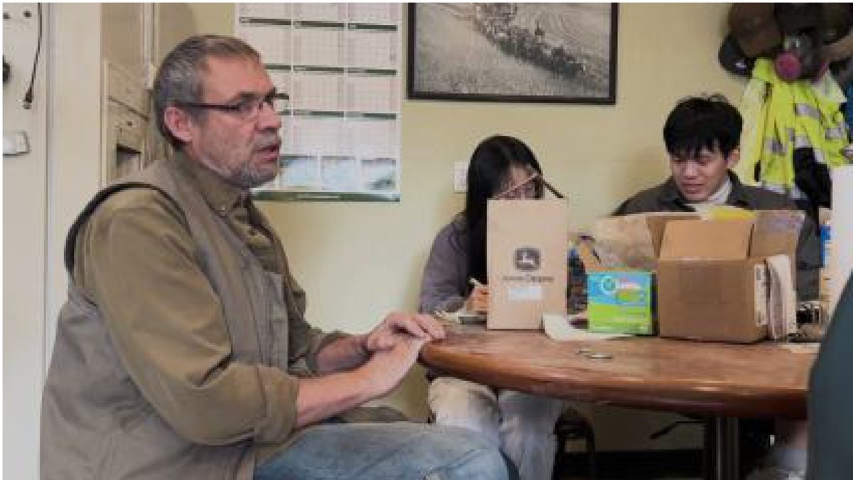 A farmer talking with team members at a table
