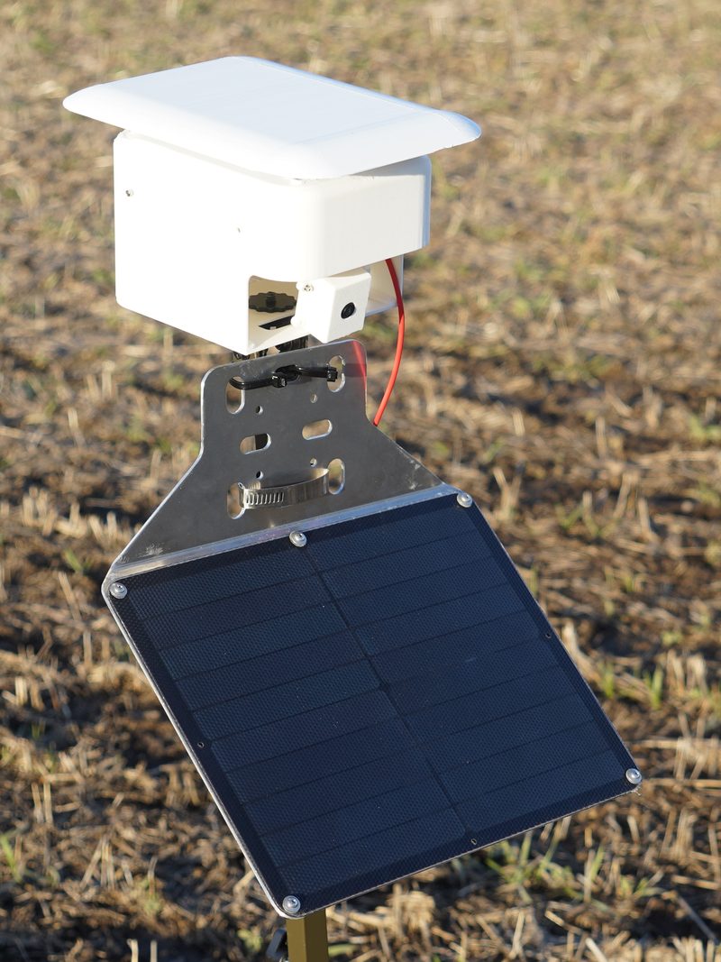 FarmGazer 2.0: a white 3D-printed enclosure with a roof overhang and the camera in its own housing, above a solar panel